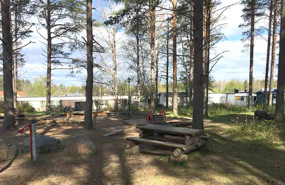 Sittbänk med bord i ena änden av lekparken