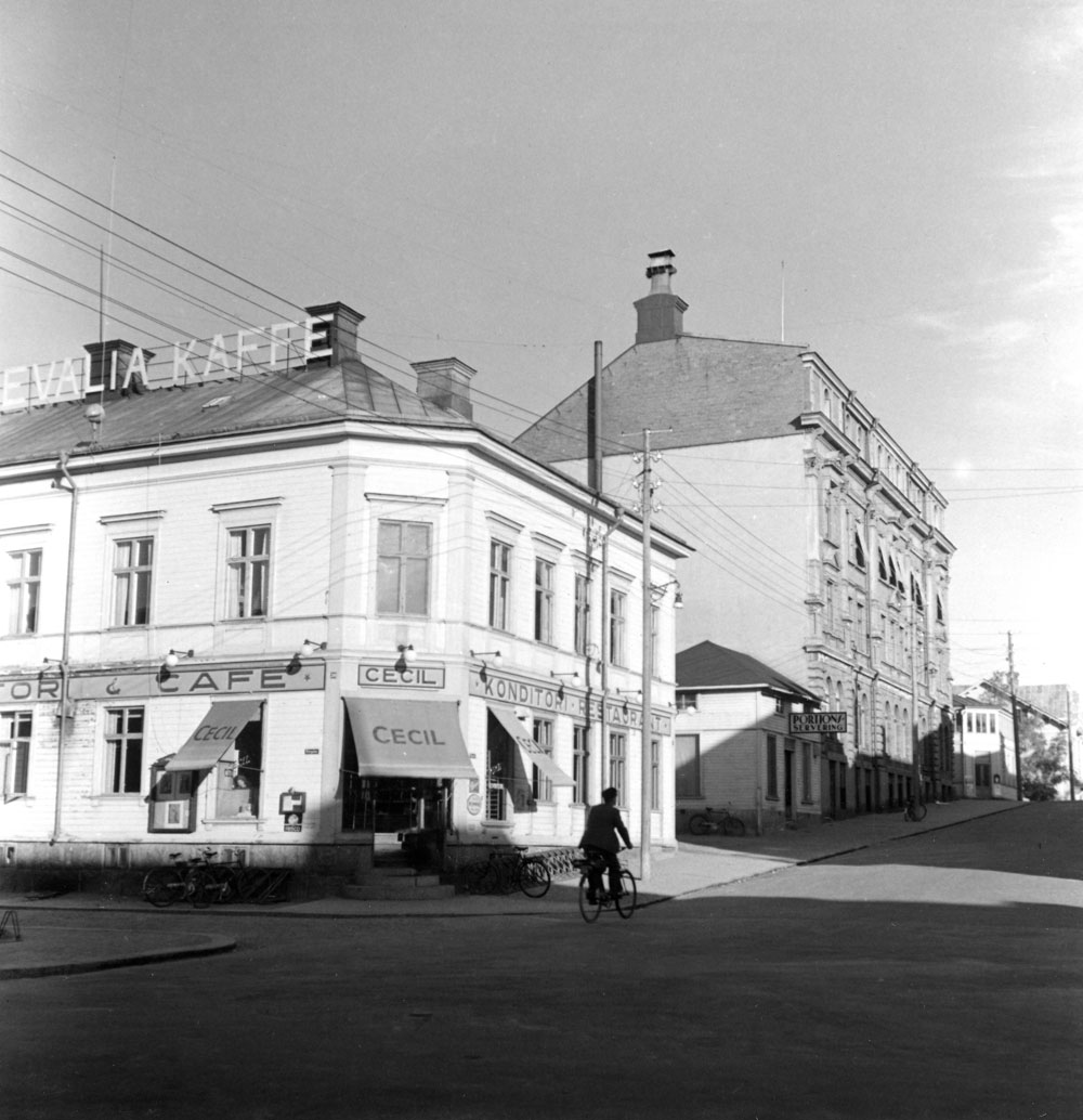 Gatumiljö med kafé i hörnhus.